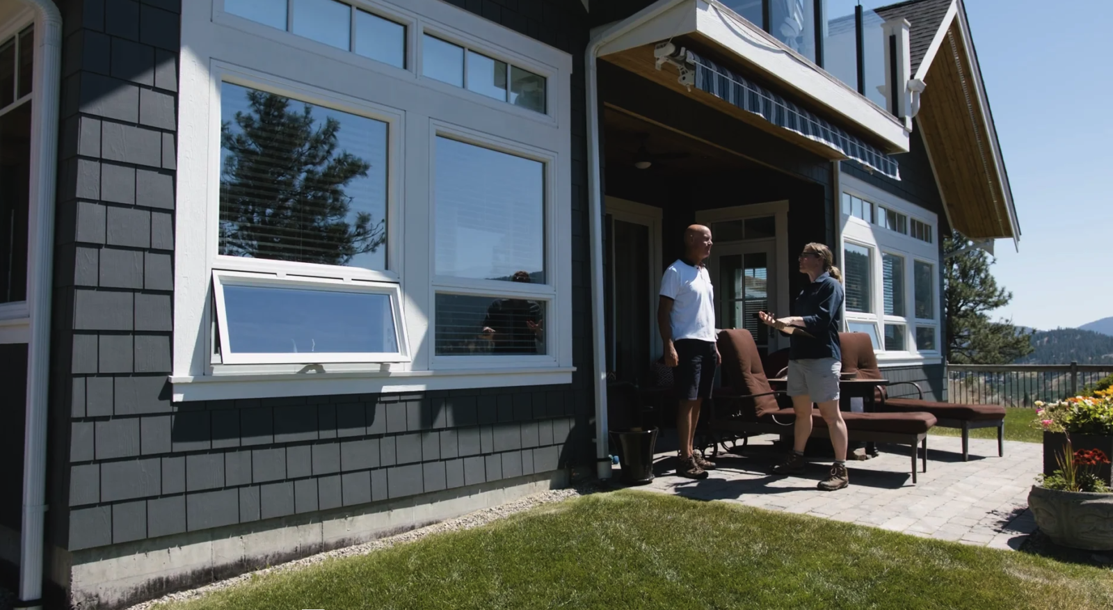 Two people are standing and talking on the patio of a house