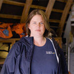 A woman in an Emergency Management BC jacket stands in a storage area