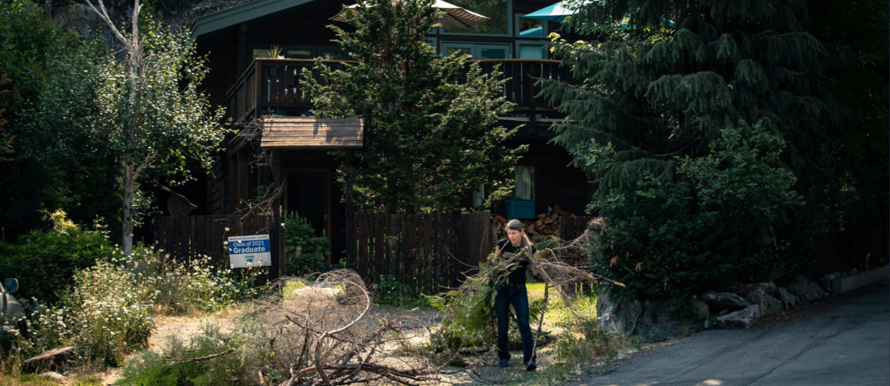 Woman clearing branches in front of a house