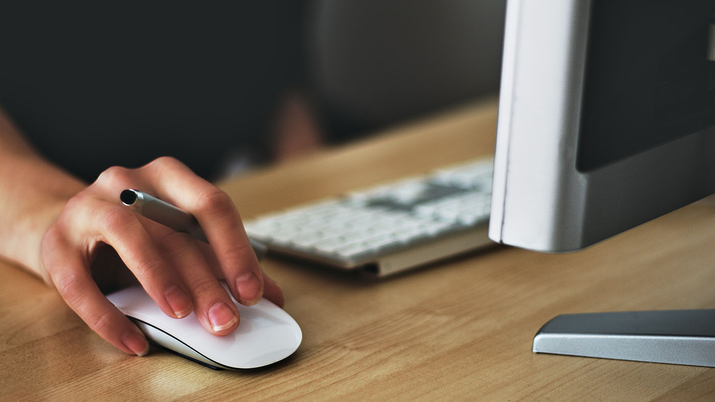 A close-up of a person using a computer mouse at a desk.