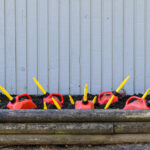 Several red gasoline cans with yellow spouts are placed in a planter box