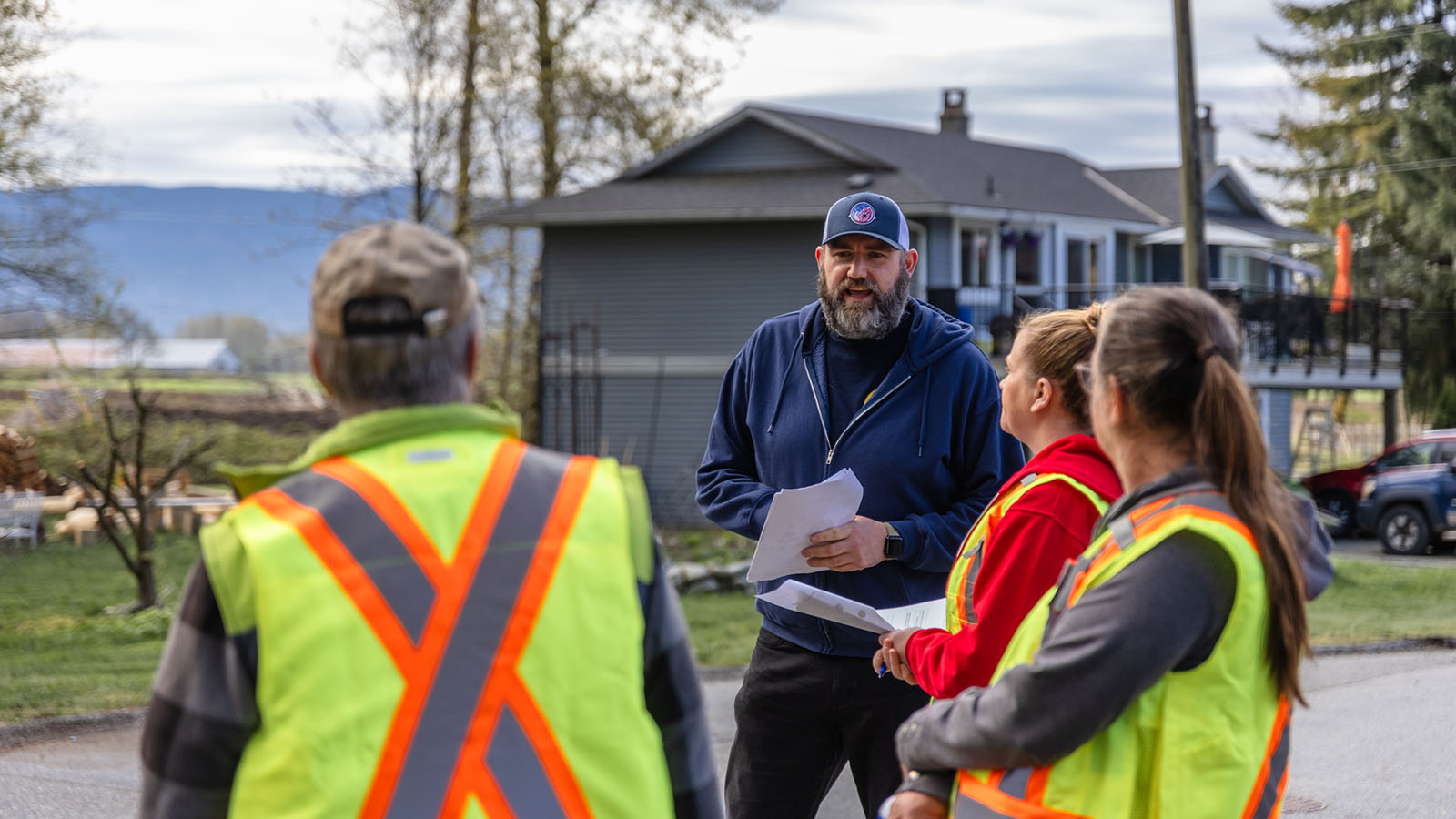 Man holding papers talking to three people in safety vests