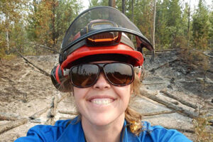 A headshot of a woman with sunglasses and a hardhat