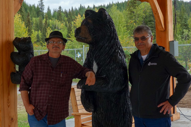 2 men with a bear statue in between them